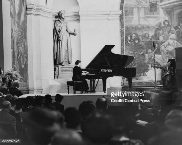 British pianist Dame Myra Hess entertains workers during their lunchtime at the Royal Exchange, London, World War II, 30th June 1942.