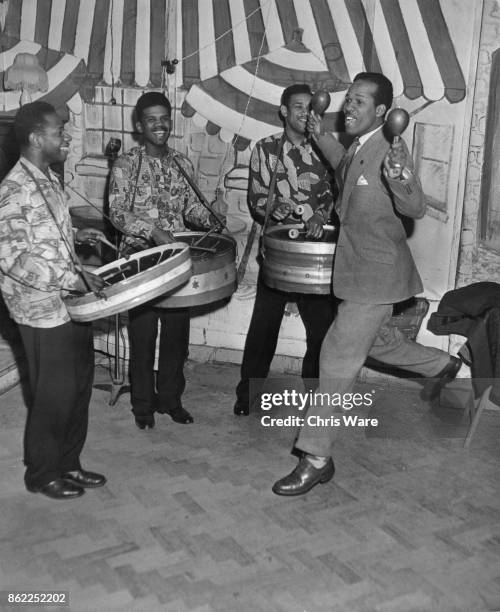 British athlete Emmanuel McDonald Bailey accompanies the Trinidad All-Steel Band on maracas during a rehearsal, UK, April 1953. Bailey was born in...