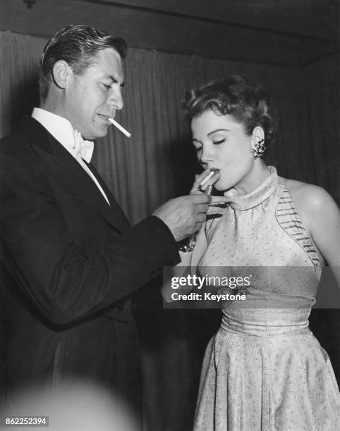 American actor John Hodiak lights a cigarette for his wife, actress Anne Baxter , USA, 18th May 1950.