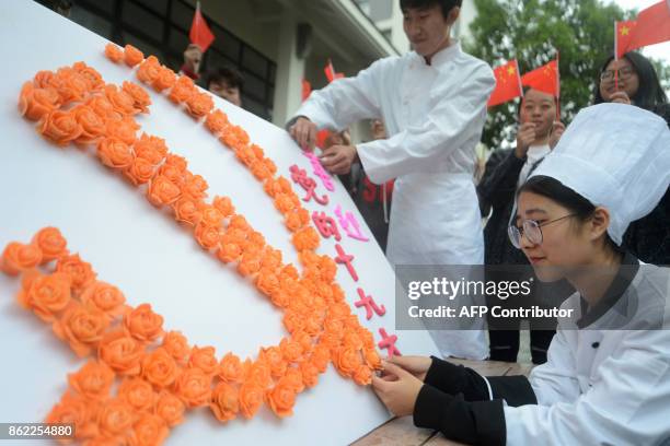 Students from a tourism and cooking college in Yangzhou University form the emblem of the Chinese Communist Party of China with carrots carved in the...