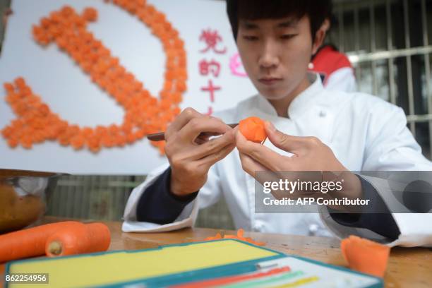 Student from a tourism and cooking college in Yangzhou University carves a carrot in the shape of a flower to form the emblem of the Chinese...