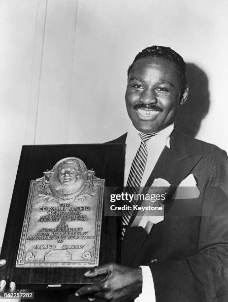 World Heavyweight Champion Ezzard Charles receives the Edward J. Neil Memorial Boxing Plaque for outstanding service to boxing from the Boxing...