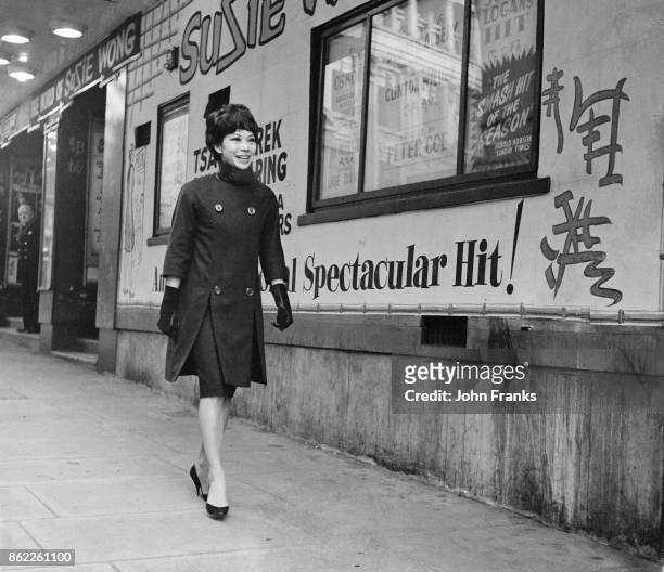 Actress Jacqueline Chan, aka Jacqui Chan, walks past posters of the play 'The World of Suzie Wong' outside the Prince of Wales Theatre in London,...