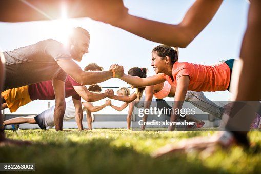 Happy athletic people cooperating while exercising on a sports training. Happy athletic people cooperating while exercising on a sports training.