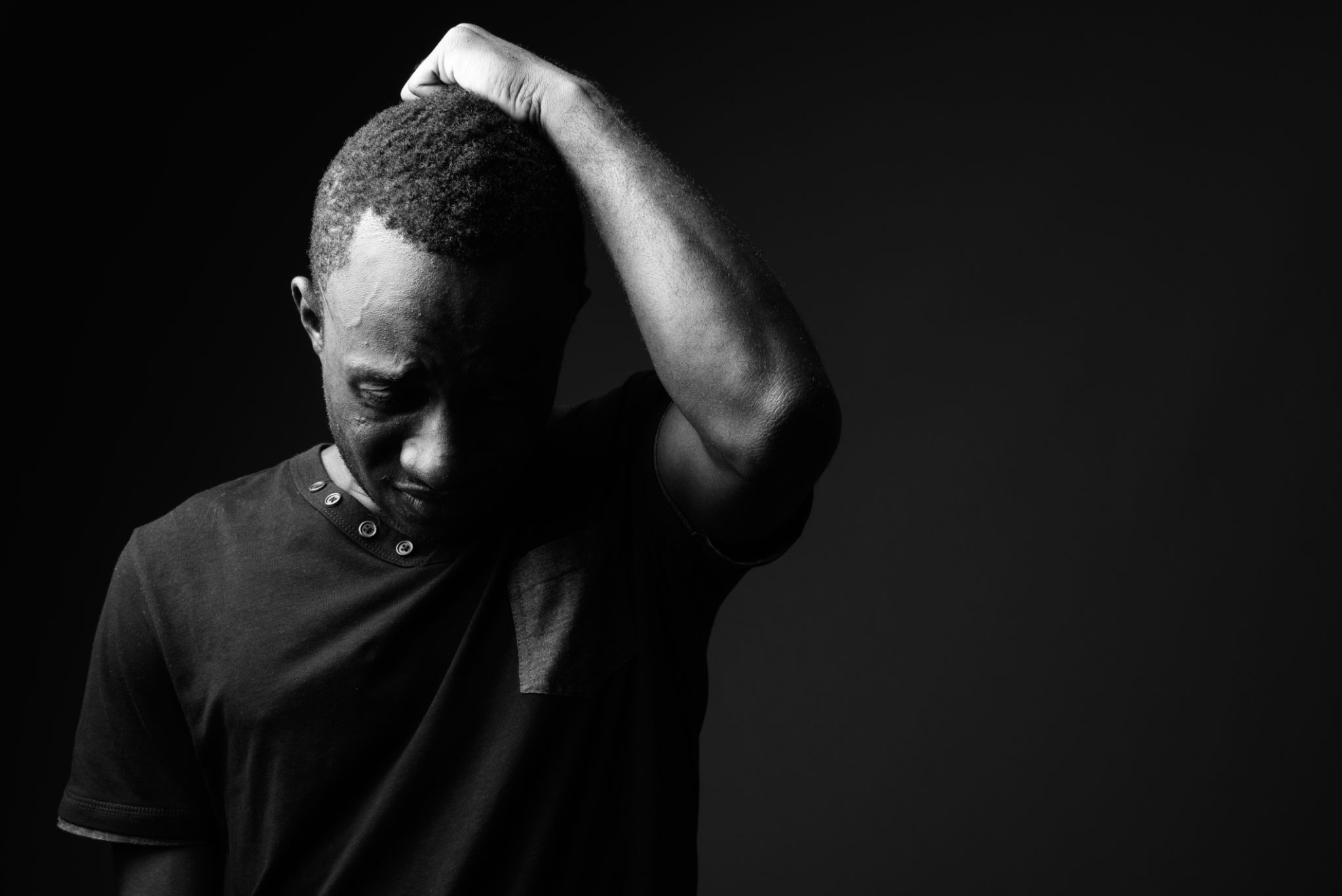 Studio shot of young African man wearing black shirt in black and white Studio shot of young African man wearing black shirt in black and white