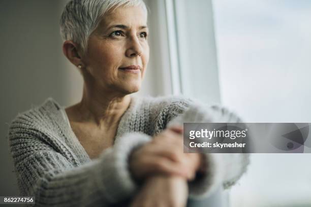 portrait of beautiful mature woman relaxing by the window. - short hair stock pictures, royalty-free photos & images