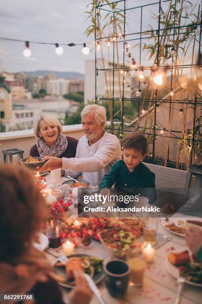 grandparents with grandson at a dinner party - multi generation family christmas stock pictures, royalty-free photos & images