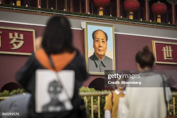 Visitors take photographs in front of a portrait of former Chinese leader Mao Zedong at Tiananmen Square in Beijing, China, on Monday, Oct. 16, 2017....