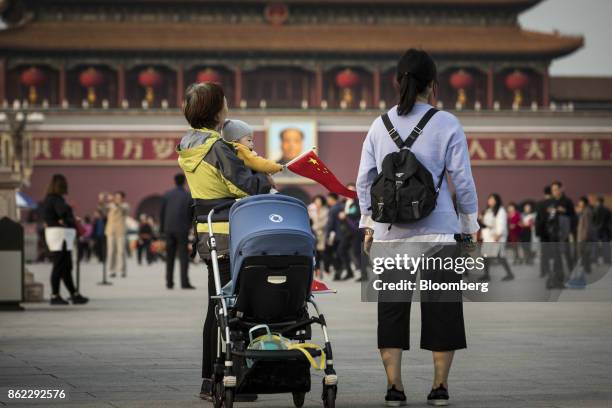 Child holds a Chinese flag while tourists and pedestrians walk past a portrait of former Chinese leader Mao Zedong at Tiananmen Square in Beijing,...