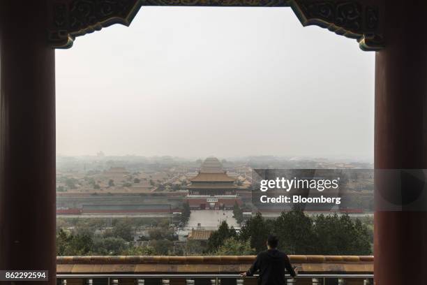 Visitor sits in a pavilion at the top of Jingshan Park as haze shrouds the Forbidden City in Beijing, China, on Tuesday, Oct. 17, 2017. President Xi...
