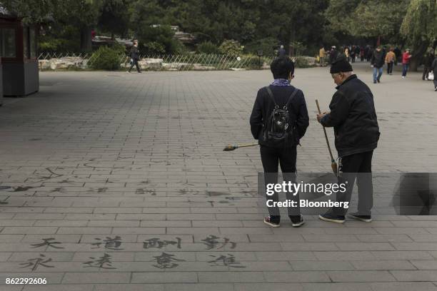 Visitors hold calligraphy brushes as they practice Chinese calligraphy with water at Jingshan Park in Beijing, China, on Tuesday, Oct. 17, 2017....
