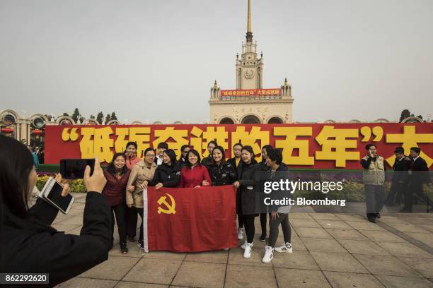 Visitors pose for a photograph with the Chinese Communist Party flag outside the Beijing Exhibition Center showing the "Five Years of Sheer Endeavor"...