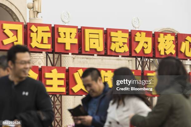 Visitors walk past a slogan referencing Chinese President Xi Jinping displayed outside the Beijing Exhibition Center showing the "Five Years of Sheer...