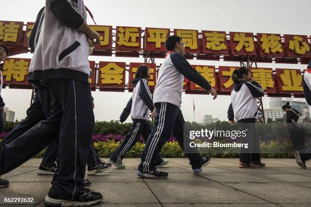 School students walk past a slogan referencing Chinese President Xi Jinping displayed outside the Beijing Exhibition Center in Beijing, China, on...