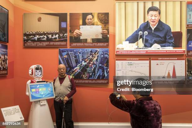 Visitor poses for a photograph next to a robot at the "Five Years of Sheer Endeavor" show at the Beijing Exhibition Center in Beijing, China, on...