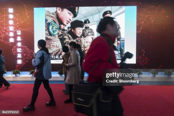 Attendees walk past a photo slideshow of Chinese President Xi Jinping on display at the "Five Years of Sheer Endeavor" show at the Beijing Exhibition...