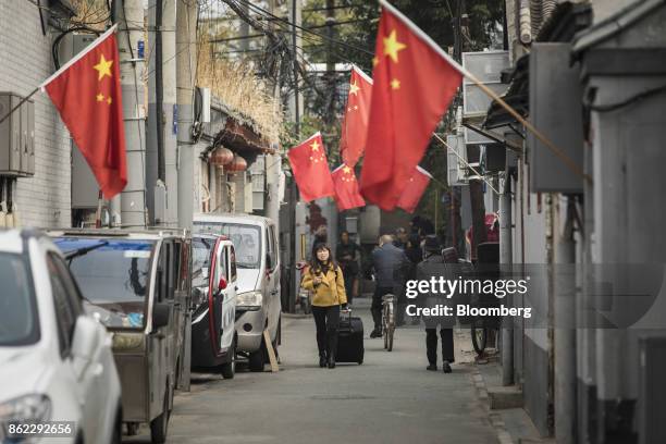 Chinese flags hang on display as a woman pulls a suitcase through a street in Beijing, China, on Tuesday, Oct. 17, 2017. President Xi Jinping is...
