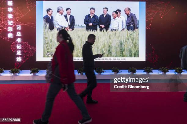 Attendees walk past a photo slideshow of Chinese President Xi Jinping on display at the "Five Years of Sheer Endeavor" show at the Beijing Exhibition...
