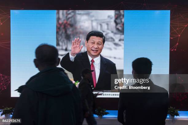 Attendees look at a photo slideshow of Chinese President Xi Jinping on display at the "Five Years of Sheer Endeavor" show at the Beijing Exhibition...