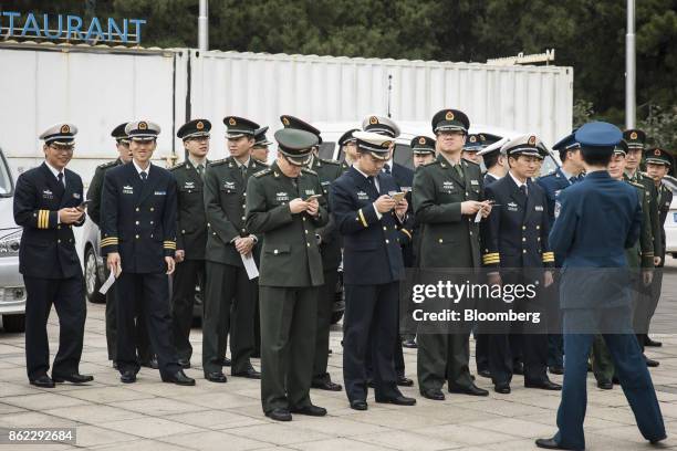 Members of the Chinese People's Liberation Army check their smartphones as they line up outside the Beijing Exhibition Center for the "Five Years of...