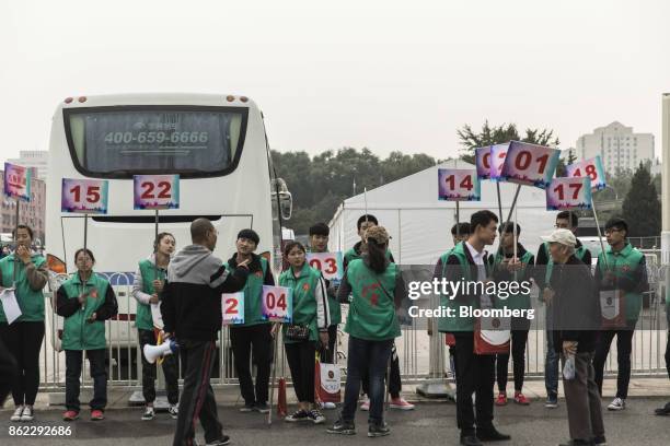 Volunteers hold up signs for different tour groups visiting the "Five Years of Sheer Endeavor" show at the Beijing Exhibition Center in Beijing,...