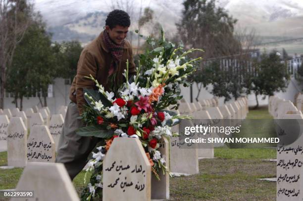 An Iraqi Kurdish man lays flowers on the grave of a relative killed in the Halabja attacks in 1988 in the northern town of Halabja on January 26,...