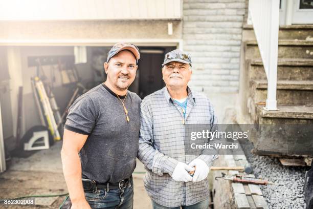 senior father and his adult son renovating their house - blue collar worker family stock pictures, royalty-free photos & images