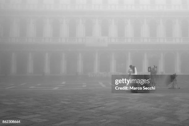 Photographers take a picture of a bride and groom in Saint Mark's Square under heavy fog on October 17, 2017 in Venice, Italy. Venice and the lagoon...