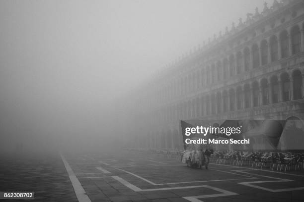 Street seller pushes his stall in Saint Mark's square on October 17, 2017 in Venice, Italy. Venice and the lagoon woke up this morning under a heavy...