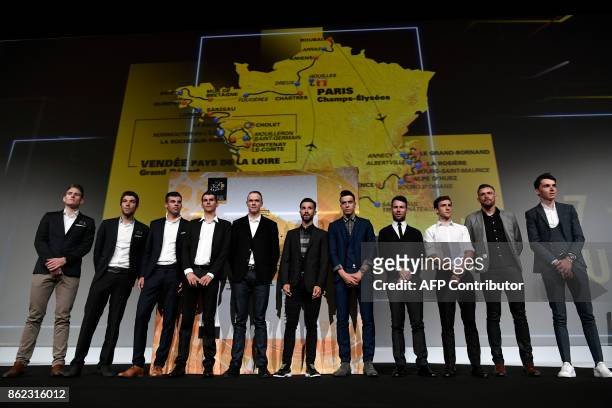 Competitors pose in front of a map of the official route of the 2018 edition of the Tour de France cycling race during its presentation in Paris, on...