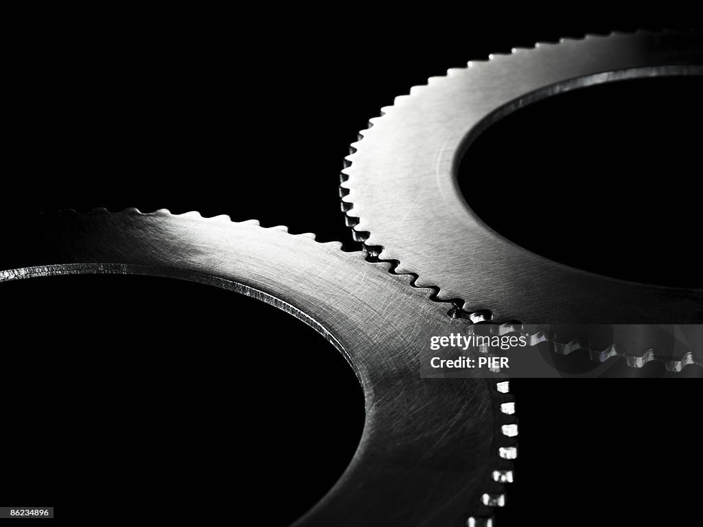 Two linked steel gear / cogs on black background