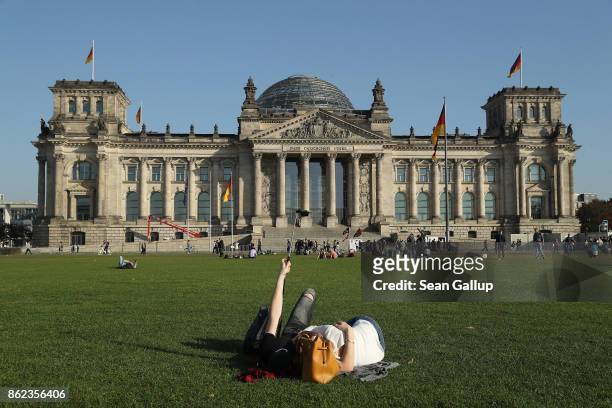 People relax on the lawn in front of the Reichstag, seat of the Bundestag, on October 17, 2017 in Berlin, Germany. Following German federal elections...