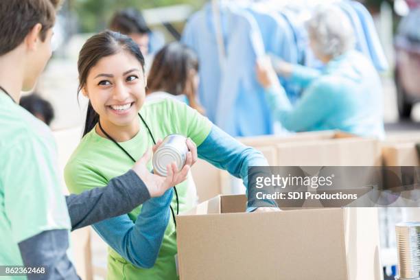 male and female volunteers sort donations during food drive - charity and relief work stock pictures, royalty-free photos & images