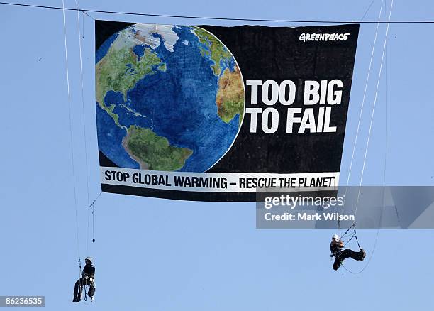 Greenpeace protesters hang with a banner from a construction crane on 23rd street near the State Department on April 27, 2009 in Washington, DC. The...