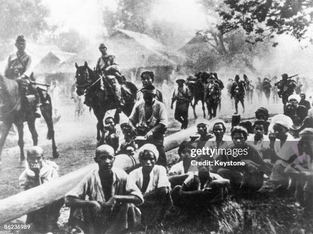 Burmese locals show little interest in the arrival of the Japanese occupying forces in their village, during World War II, circa 1942.