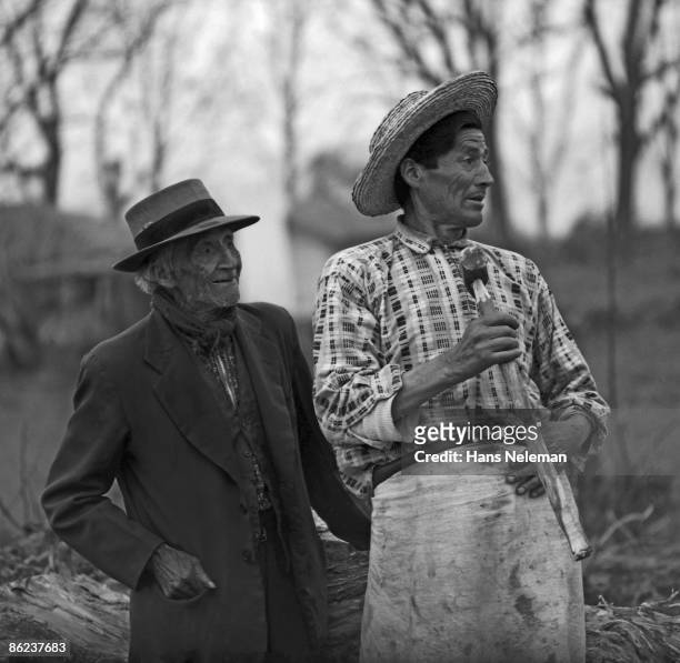 Portrait of a pair of elderly men, on in a jacket and fedora and fhen other, somewhat younger, in an apron, straw hat and carrying a hammer, Fundo La...