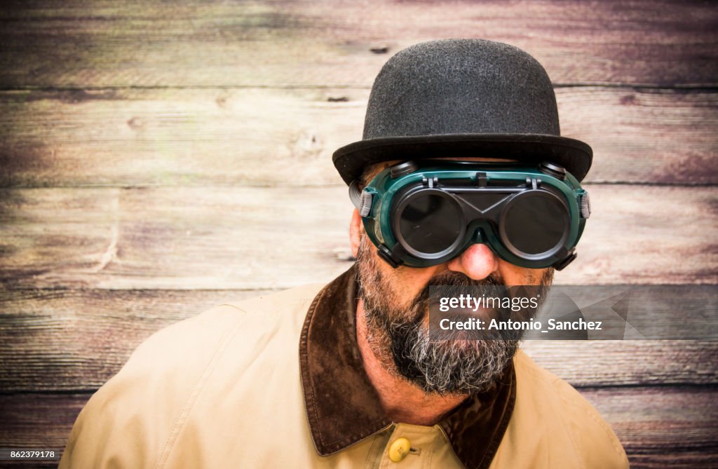 Hombre Con Barba Jugador De Bolos Impermeable Y Unas Extrañas Gafas  Futuristas Sobre Fondo De Madera Foto de stock - Getty Images