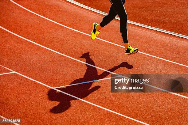 sportsperson running over the running track - high contrast athlete stock pictures, royalty-free photos & images