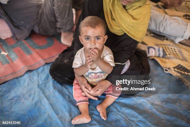 Woman who fled the Islamic State controlled area of Raqqa holds her child inside a tent at a makeshift camp of Ain Issa 50 kilometers north of Raqqa...