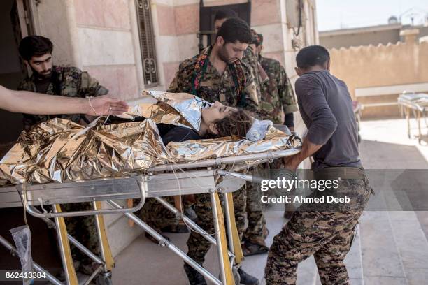 Members of the US-backed Syrian Democratic Forces carry a wounded woman at a military field hospital who was injured by a mine that exploded near...