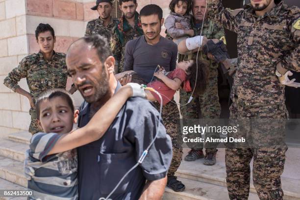 Fighters carry children who were injured by a mine which exploded when a group of civilians were escaping the Islamic State controlled areas of Raqqa...