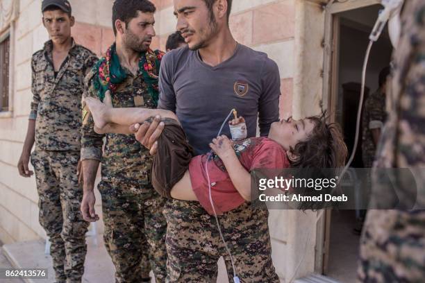 Member of the US-backed Syrian Democratic Forces holds a girl who was injured by a mine which exploded when a group of civilians were escaping the...
