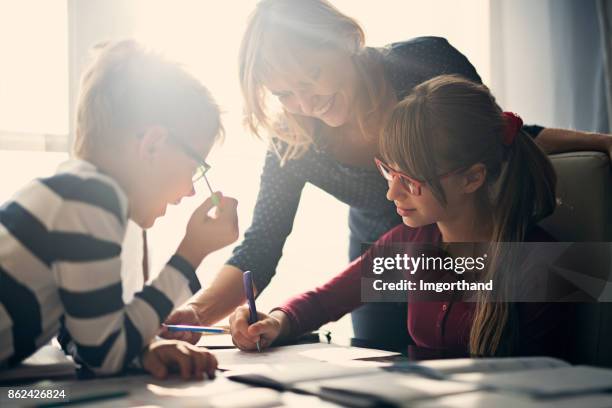 mutter halping kinder hausaufgaben machen - forschung teenager stock-fotos und bilder