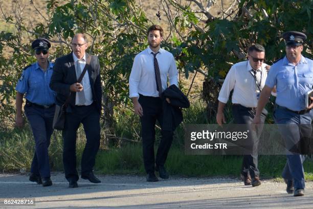 Matthew Caruana Galizia and Peter Caruana Galizia , son and husband of journalist Daphne Caruana Galizia and policemen walk past the wreckage of a...