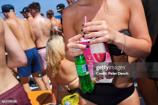 Young woman on a boat party for seasonal British workers in Ayia Napa, Cyprus, holds a carton of Sodap Dry Rose Wine.