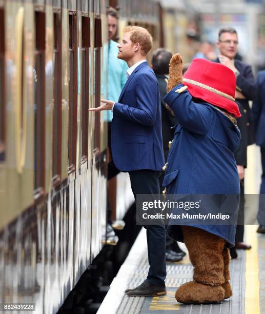 Prince Harry and Paddington Bear talk to passengers onboard the Belmond British Pullman train as they attend the Charities Forum Event at Paddington...