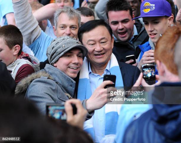 Thaksin Shinawatra, owner of Manchester City, poses for selfies with fans in the crowd during the Barclays Premier League match between Manchester...