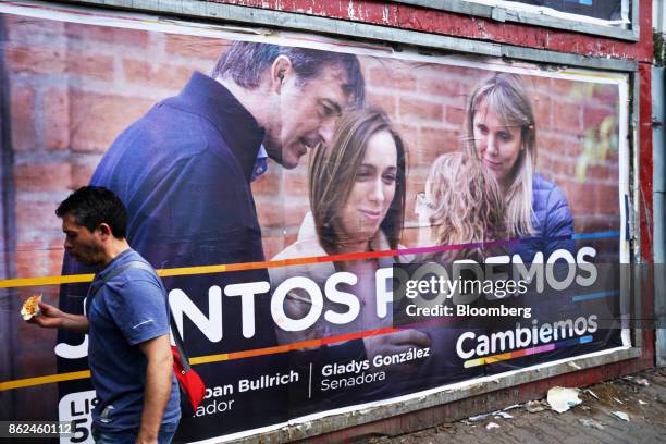 Man walk past a campaign poster for candidate Esteban Bullrich displayed on a wall in the Hurlingham neighborhood of Buenos Aires, Argentina, on...