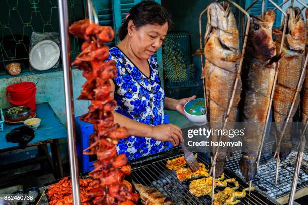 vietnamese woman preparing grilled frogs and fishes, mekong river delta, vietnam - river mekong stock pictures, royalty-free photos & images