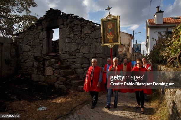 People walk past a burnt house during the funeral of a victim of a wildfire in the village of Vila Nova, near Vouzela on October 17, 2017 in Viseu...